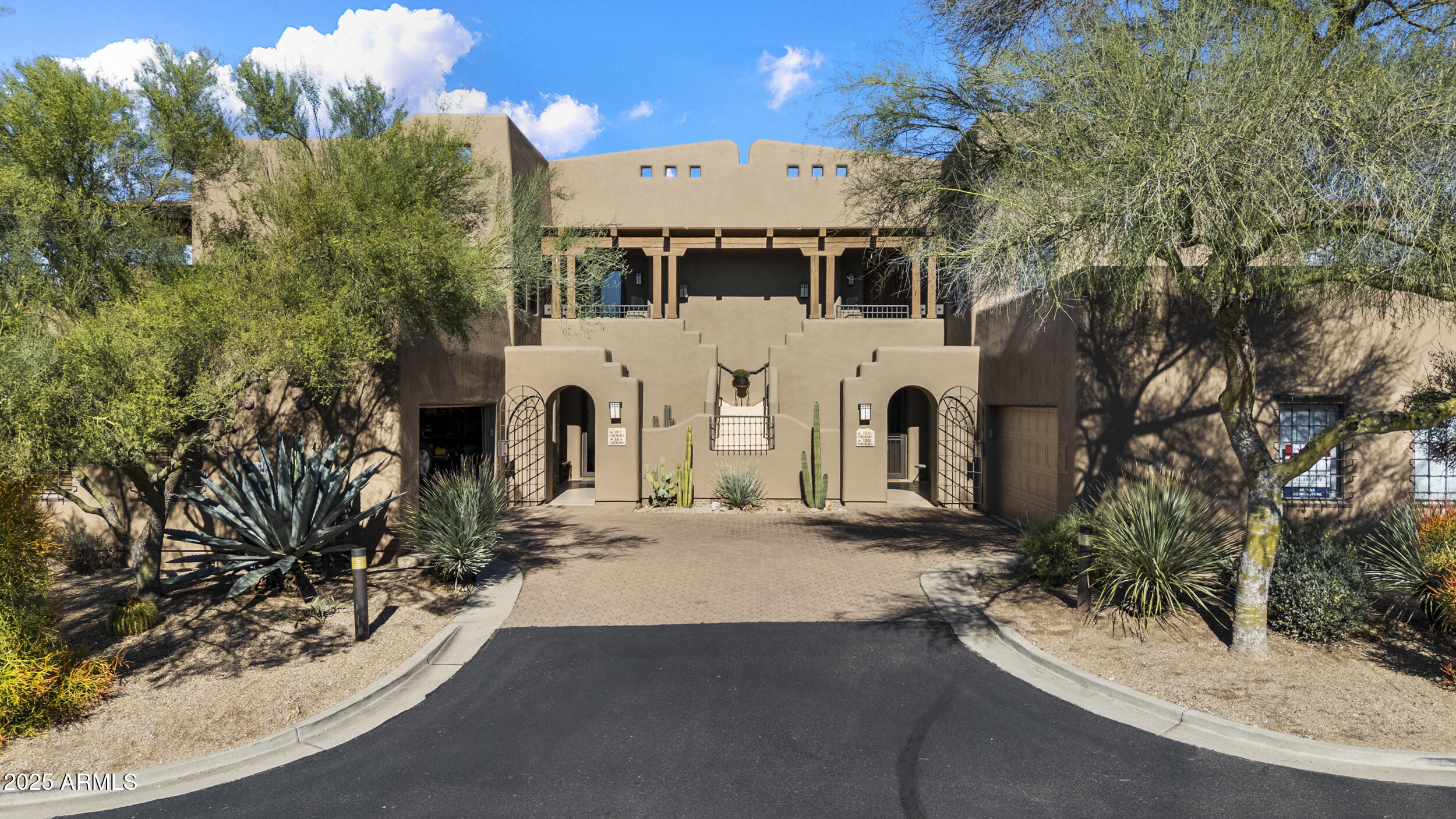 a view of a white house with large trees and plants