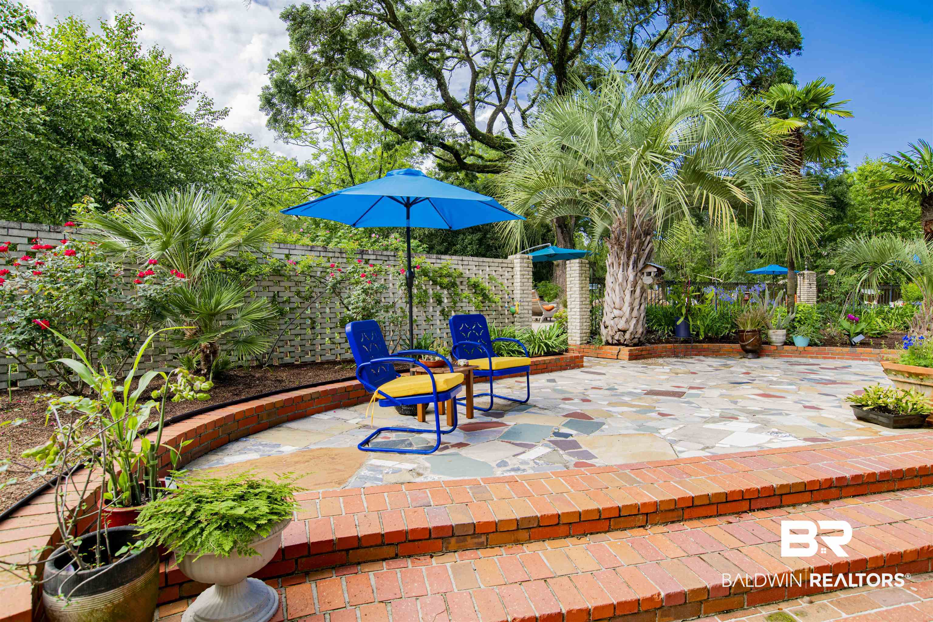 809 Bernard Circle Mobile, AL 36693 - Photo 75 of 75 Spacious patio featuring a multi-colored flagstone surface, surrounded by mature palm trees and lush greenery
