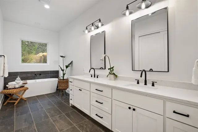 a bathroom with a double vanity sink mirror and bathtub