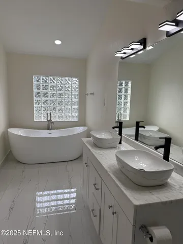 a bathroom with a tub sink and mirror