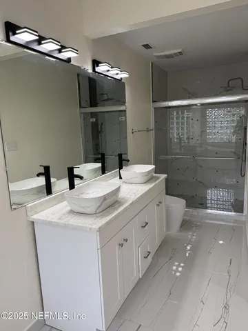 a bathroom with a granite countertop sink a toilet and shower