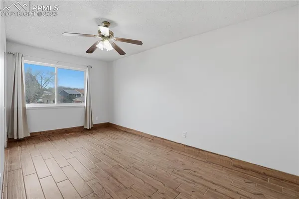 a view of an empty room with wooden floor and a window