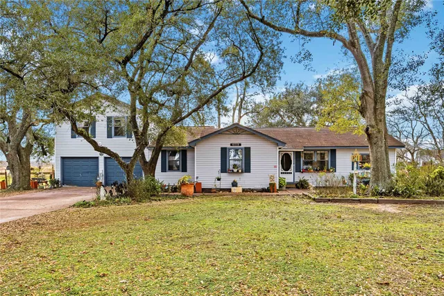 a front view of a house with a yard covered with snow and trees
