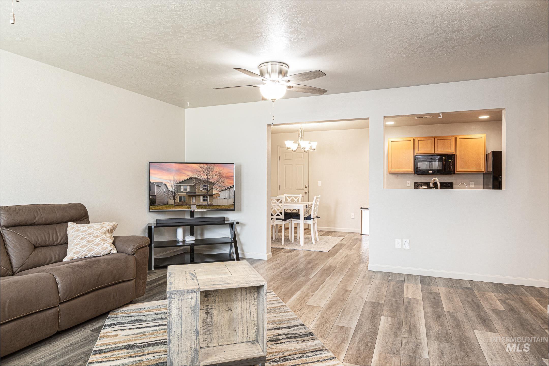 643 North Manship Avenue Meridian, ID 83642 - Photo 4 of 32 Living area featuring ceiling fan, a textured ceiling, light wood-type flooring, and hanging lights