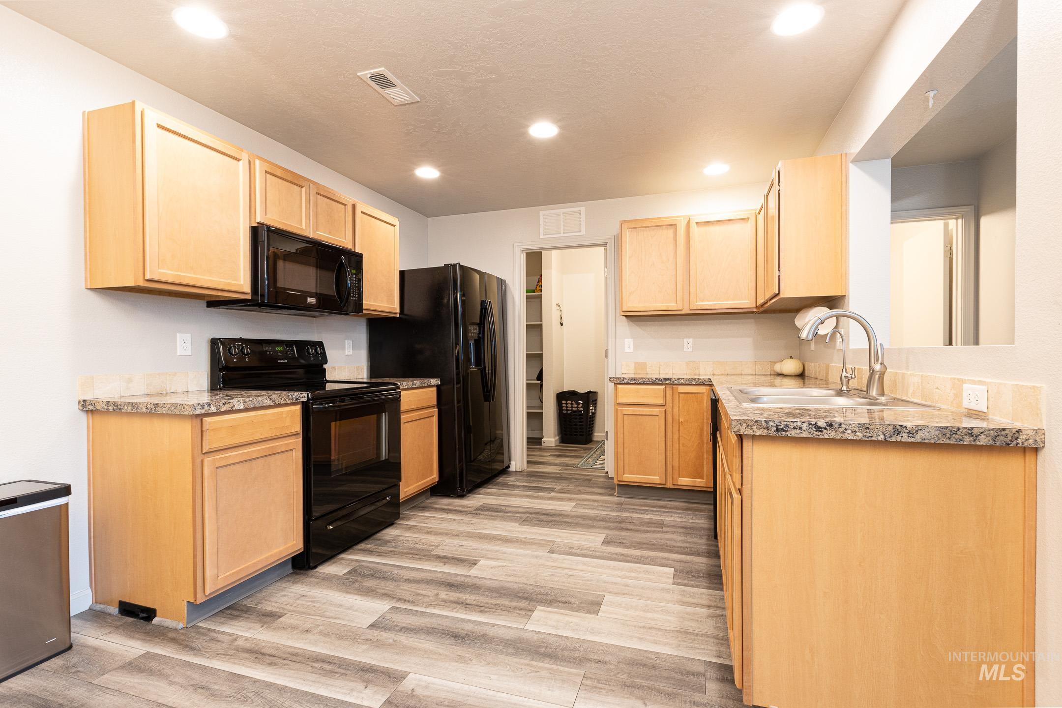 643 North Manship Avenue Meridian, ID 83642 - Photo 9 of 32 Kitchen with light wood finish cabinets, black appliances, light wood-style flooring, and recessed lighting