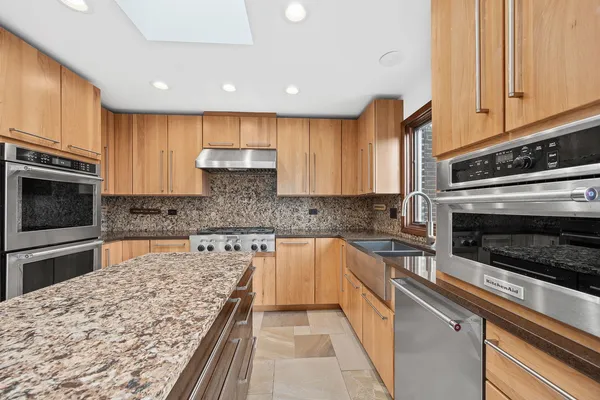 a kitchen with kitchen island granite countertop a stove sink and cabinets