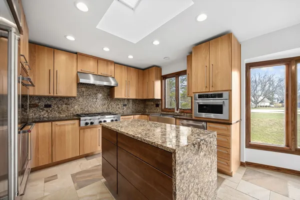 a kitchen with kitchen island granite countertop a stove sink and microwave