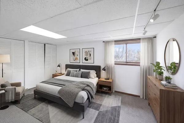 a spacious bedroom with a bed a couch and potted plant