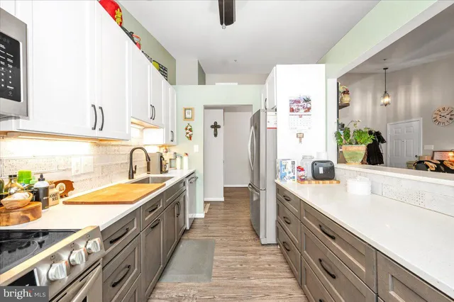 a view of a kitchen with kitchen island a sink wooden floor and stainless steel appliances