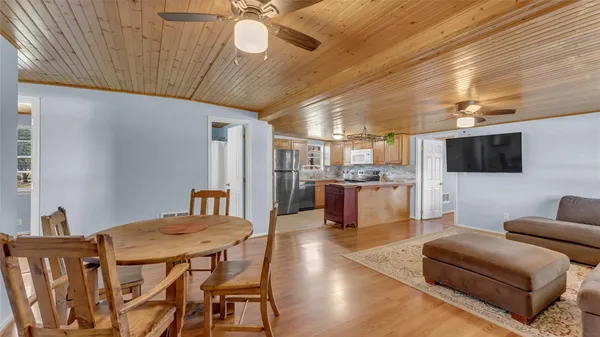 a kitchen with stainless steel appliances granite countertop a refrigerator a sink dishwasher a stove and a dining table with wooden cabinet