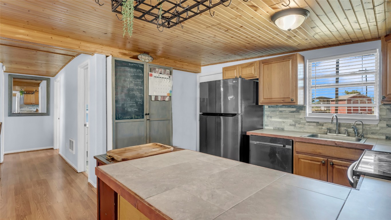 1415 Bee Lane Tow, TX 78672 - Photo 23 of 39 a kitchen with stainless steel appliances granite countertop a refrigerator a sink dishwasher a stove and a dining table with wooden cabinet
