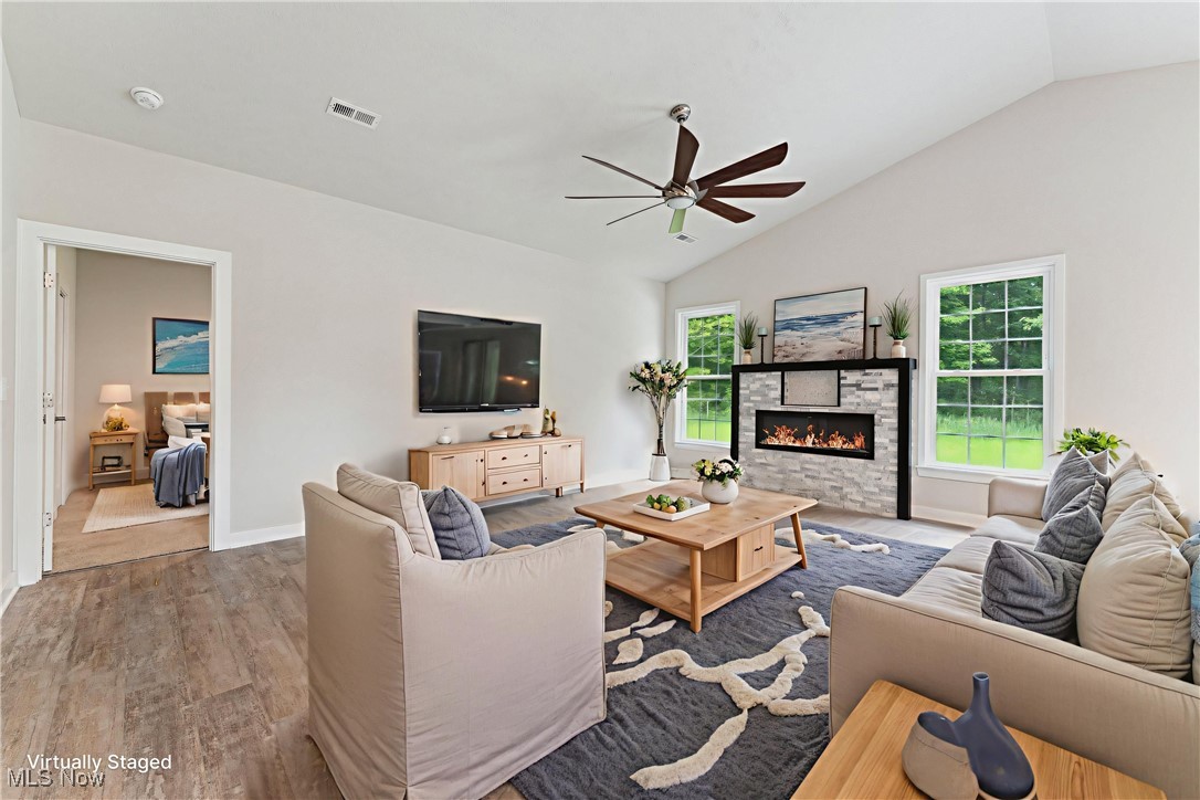 7605 Lake Road East Madison, OH 44057 - Photo 16 of 50 Virtual staging Living room with ceiling fan, lofted ceiling, wood finished floors, a stone fireplace, and plenty of natural light