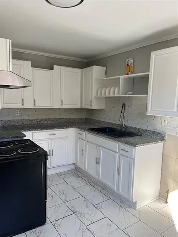 a kitchen with granite countertop a sink a stove and cabinets