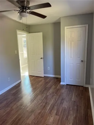 an empty room with wooden floor closet and chandelier fan