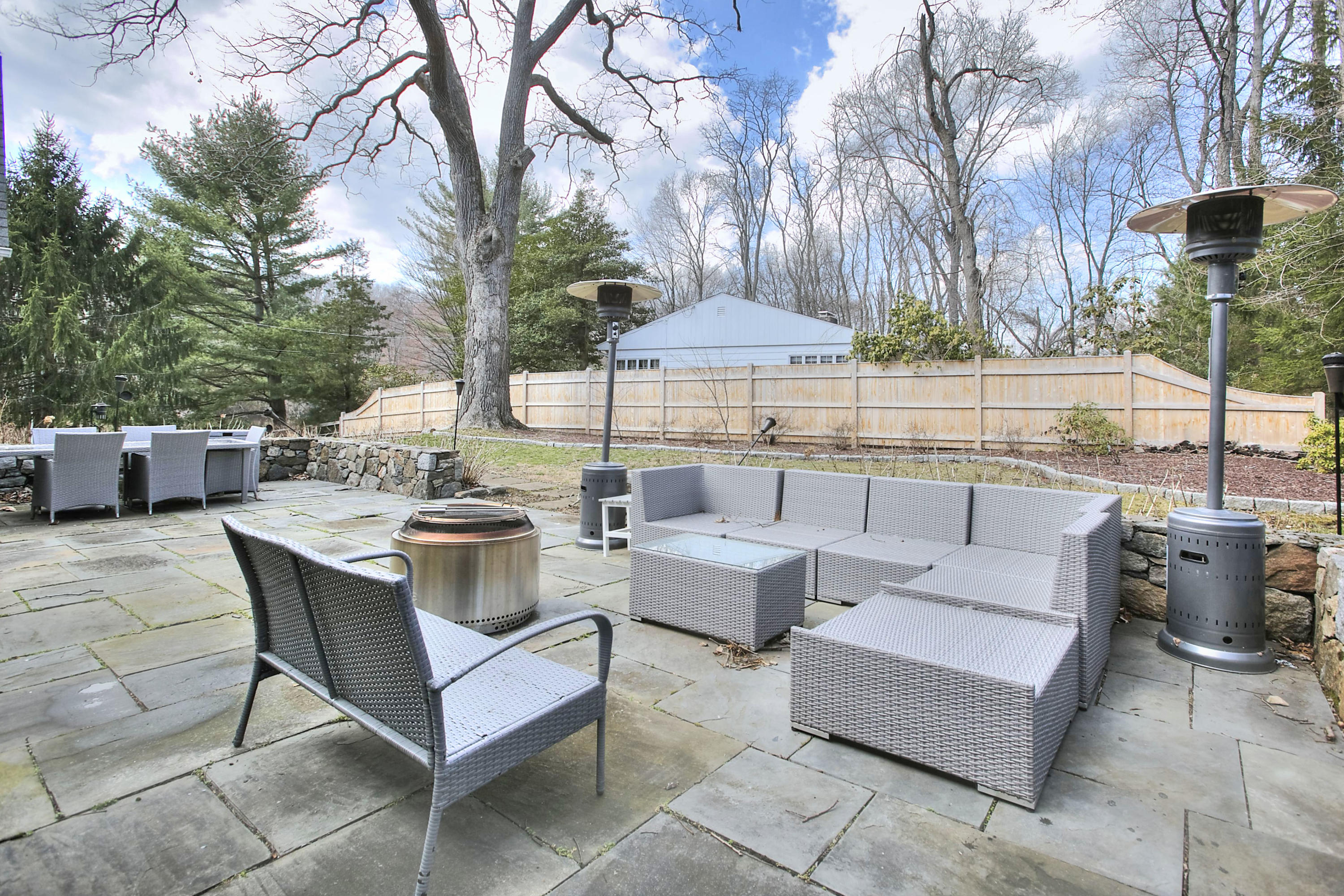 16 Arrowhead Road Wilton, CT 06897 - Photo 35 of 37 a view of a patio with couches and table and chairs under an umbrella with large trees