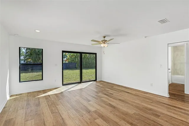 a view of an empty room with a window and wooden floor