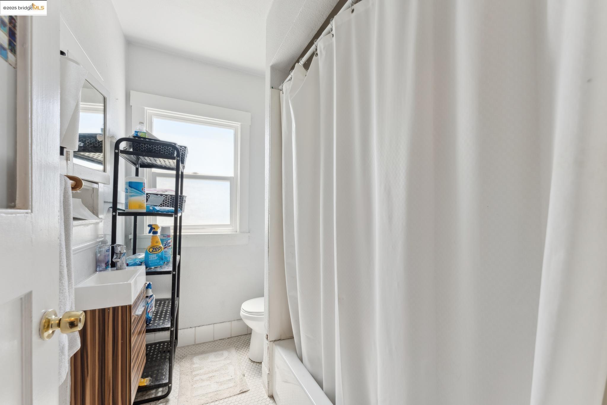 2823 11th Avenue, Unit B Oakland, CA 94610 - Photo 6 of 12 a living room with furniture and a toilet