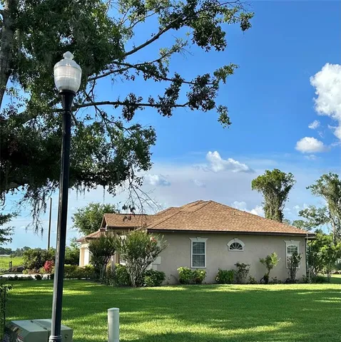 a view of a white house with a big yard and potted plants