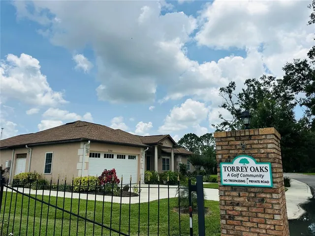 a view of a white house with a big yard and large trees