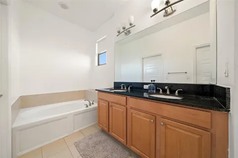 a bathroom with a granite countertop sink a mirror and bathtub