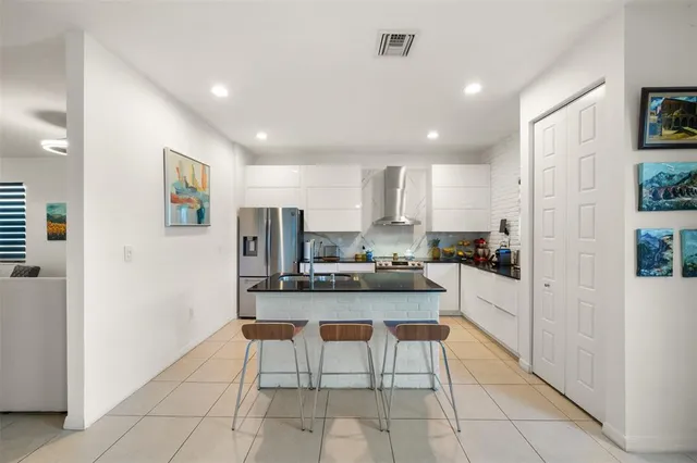 a kitchen with stainless steel appliances kitchen island granite countertop a refrigerator and a sink