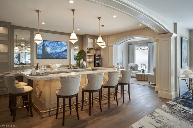 a dining hall with a dining table wooden floor and a view of kitchen
