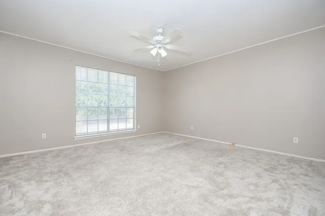 an empty room with windows and ceiling fan