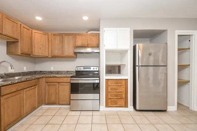 a kitchen with stainless steel appliances granite countertop a refrigerator and a stove top oven