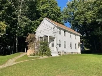 a view of a white house with a big yard and large trees