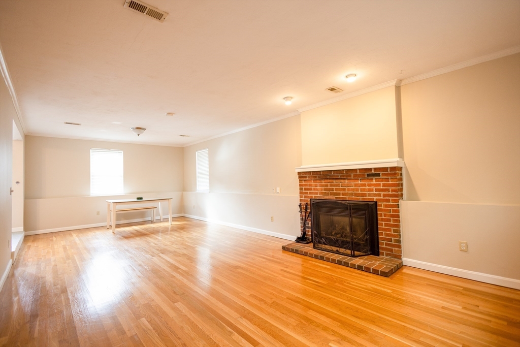 5337 B Washington Street, Unit B Boston, MA 02132 - Photo 30 of 41 an empty room with wooden floor and fireplace