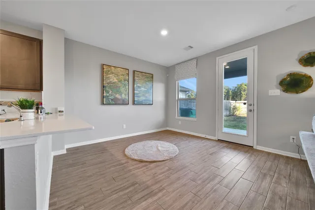 a view of an empty room with window and wooden floor