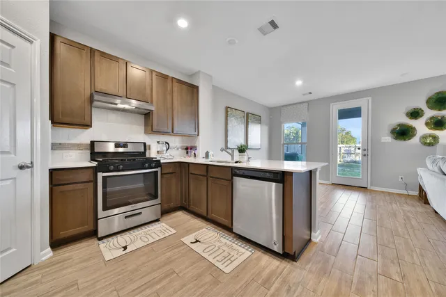 a kitchen with granite countertop a sink cabinets and stainless steel appliances