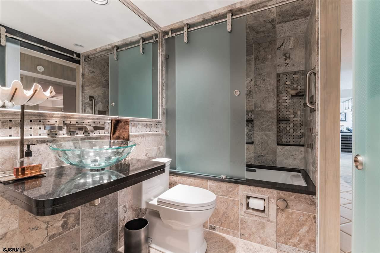 2700 Atlantic Avenue, Unit 419 Longport, NJ 08403 - Photo 17 of 32 a bathroom with a granite countertop sink a toilet and shower