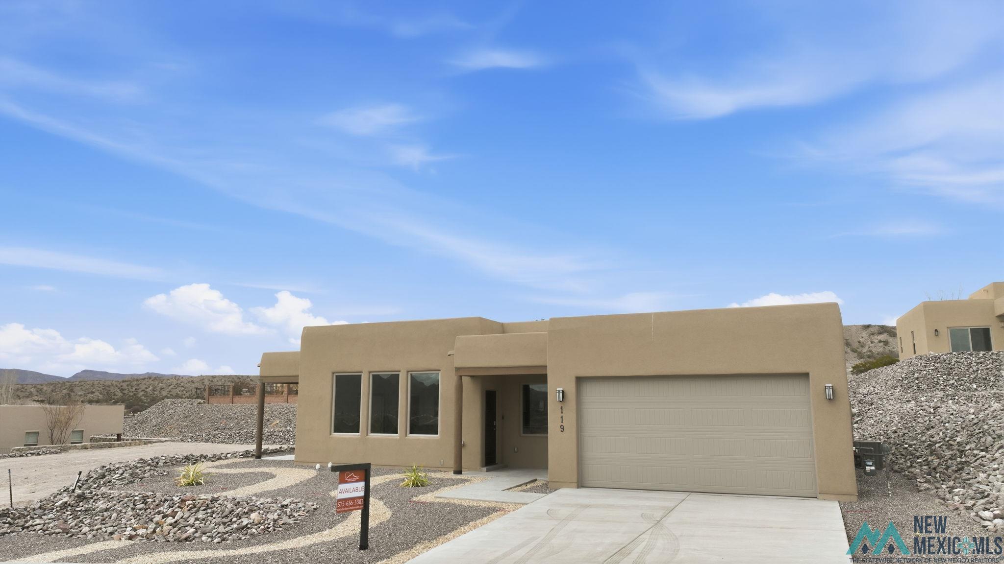 119 Mesa Grande Road Elephant Butte, NM 87935 - Photo 7 of 34 Adobe home with driveway, stucco siding, a garage, and a mountain view