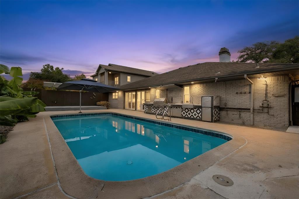 4436 Thunder Road Dallas, TX 75244 - Photo 2 of 33 Backyard with a rectangular swimming pool, concrete decking, an outdoor kitchen with built-in appliances, and a brick-faced exterior