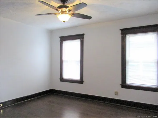 an empty room with windows and fan