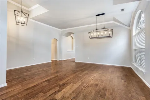 a view of an empty room with wooden floor and window