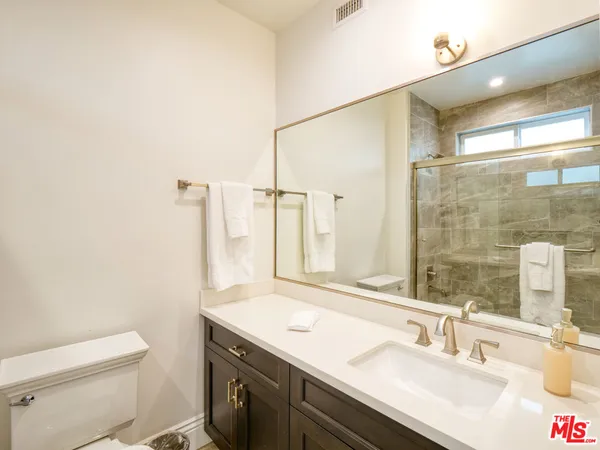 a bathroom with a granite countertop sink a toilet and a mirror