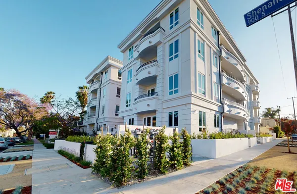 a front view of a multi story residential apartment building with garage and bench