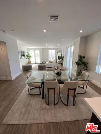 a living room with furniture kitchen view and a wooden floor