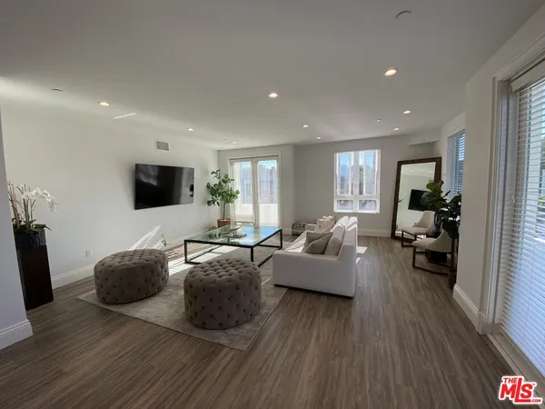 a living room with furniture a flat screen tv and a wooden floor