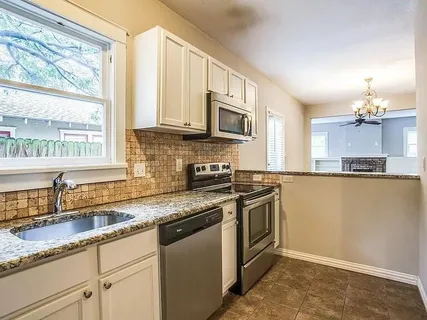 a kitchen with stainless steel appliances granite countertop a sink a stove and a granite counter tops with a window