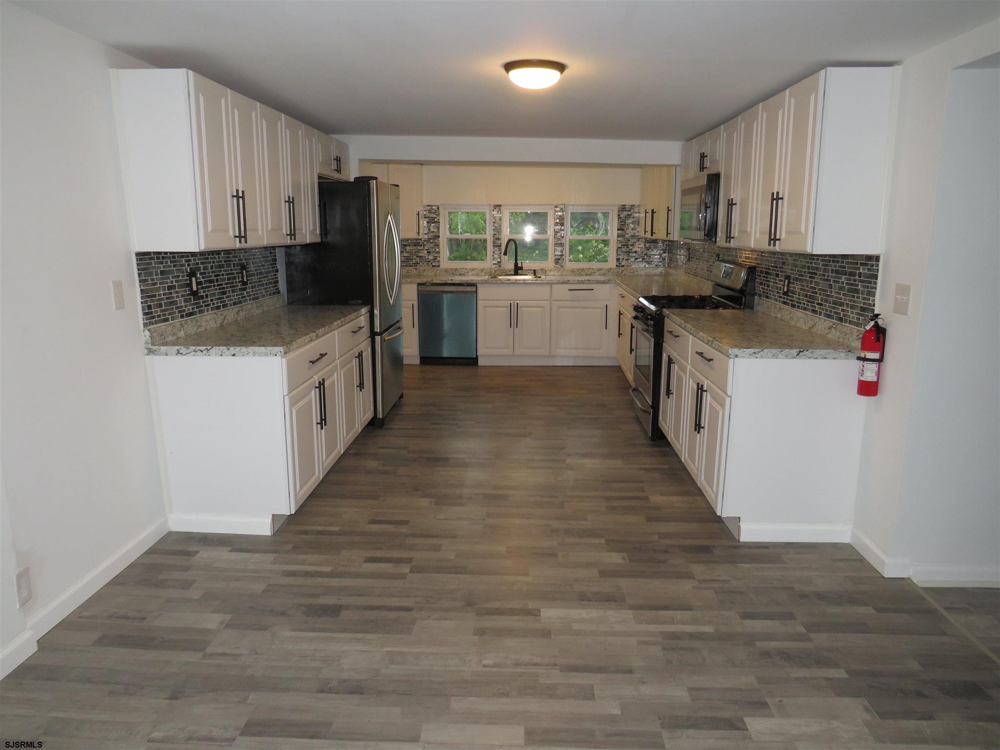 1702 Somers Point Road Egg Harbor Township, NJ 08234 - Photo 10 of 25 a kitchen with granite countertop a stove top oven a sink dishwasher and a refrigerator with wooden floor