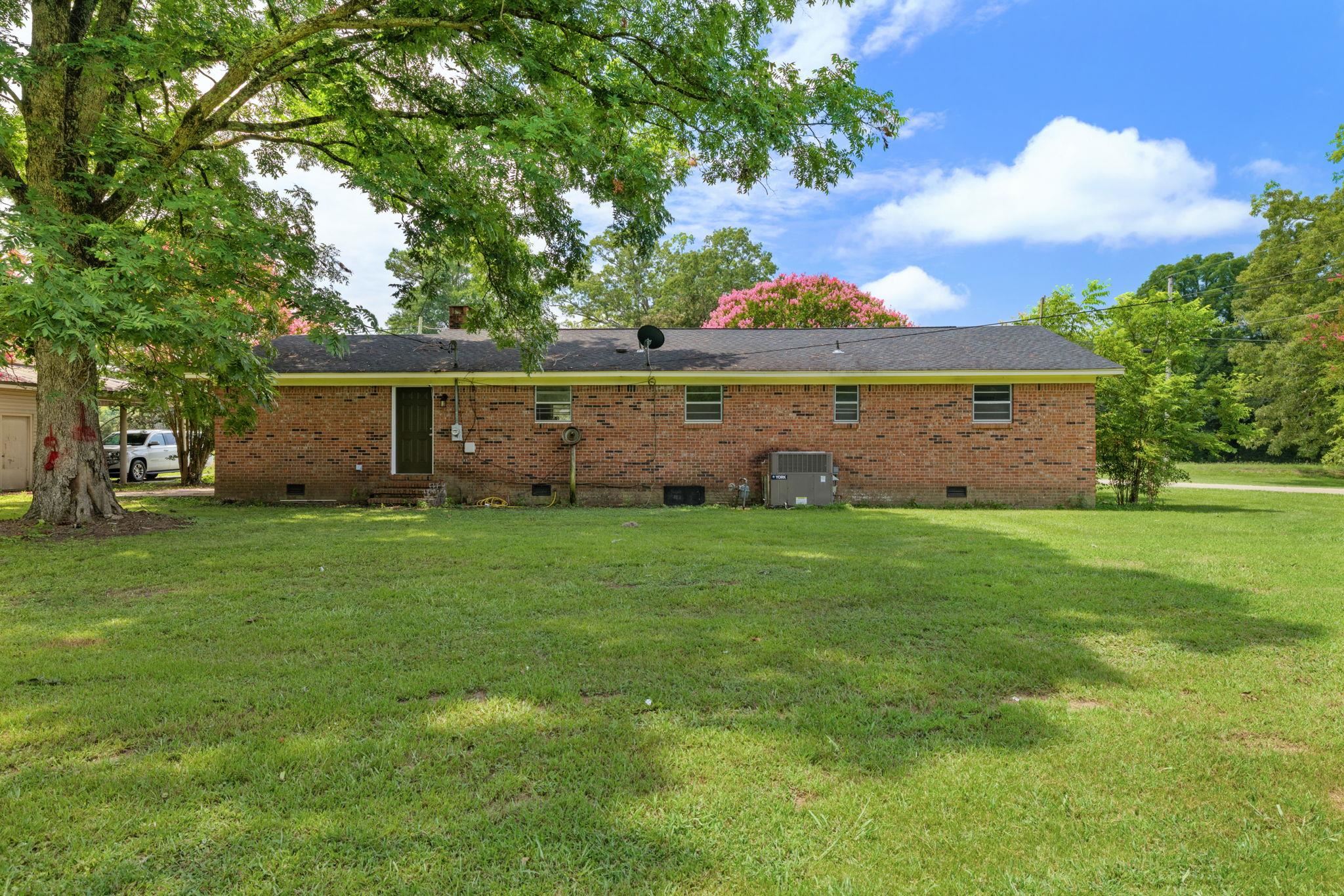217 Red Bay Road Golden, MS 38847 - Photo 22 of 33 Expansive grassy backyard featuring a brick exterior, black shingle roof, mature trees, and a detached shed