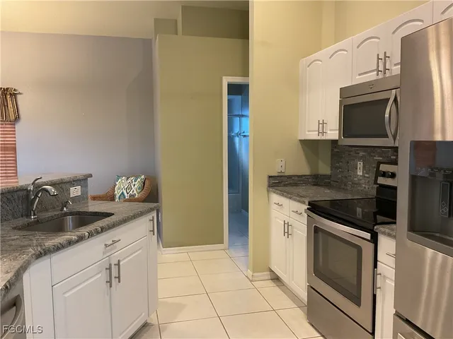 a kitchen with granite countertop a sink stove and refrigerator