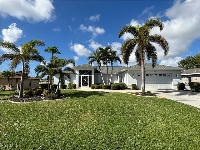 a view of a house with a yard and palm trees