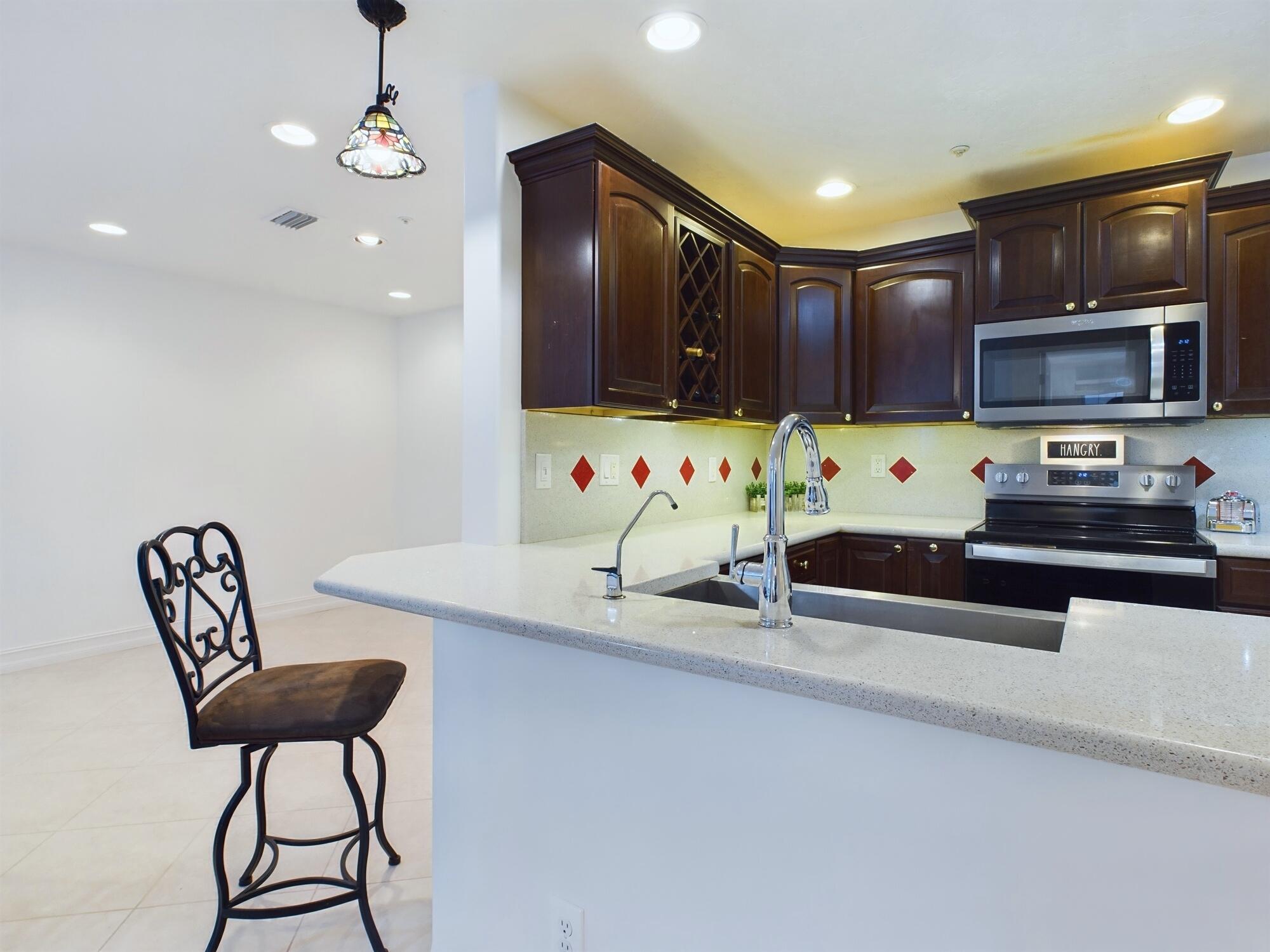 7667 North Wickham Road, Unit 1308 Melbourne, FL 32940 - Photo 11 of 56 a kitchen with stainless steel appliances granite countertop a stove a sink and a microwave
