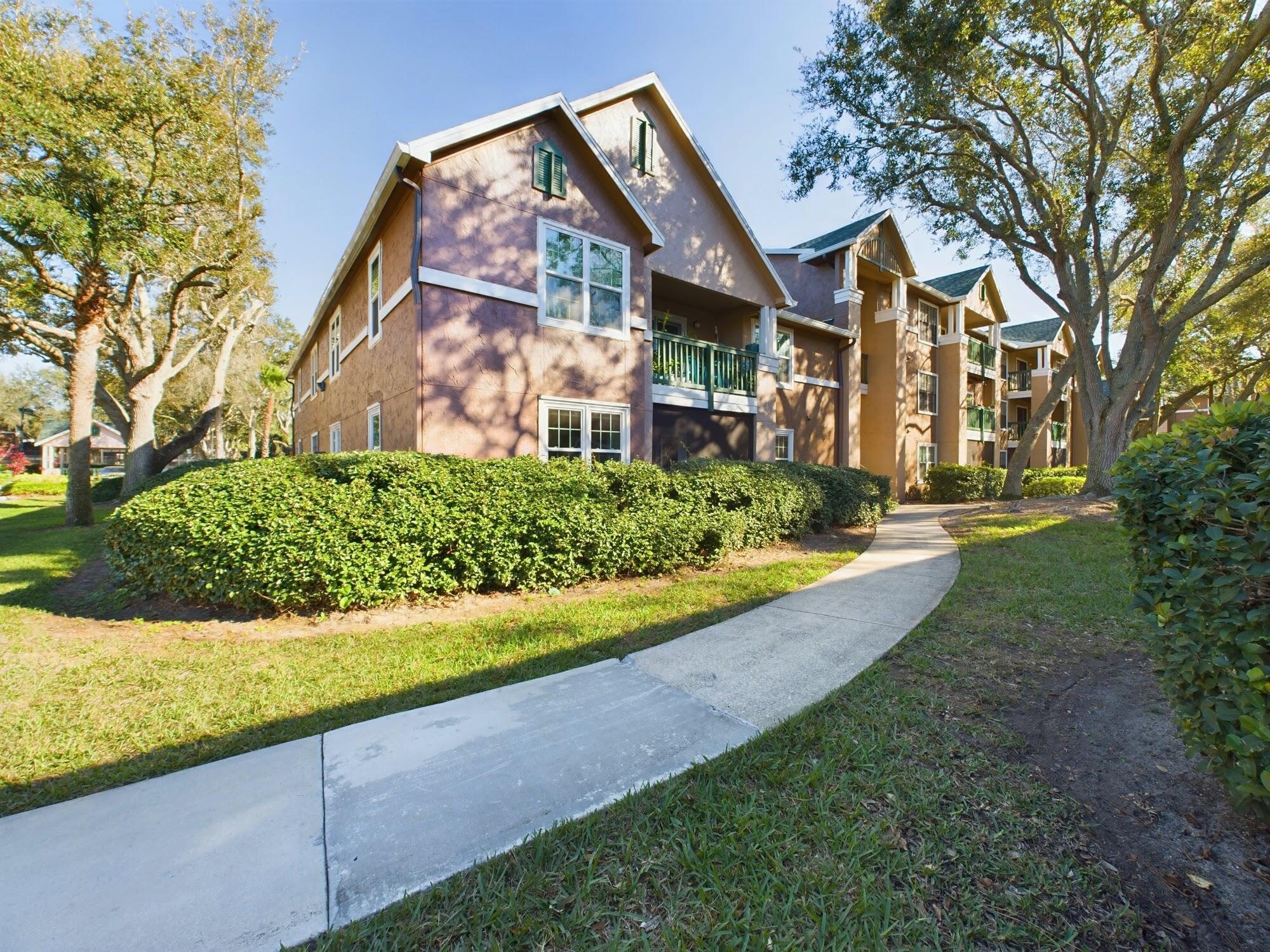 7667 North Wickham Road, Unit 1308 Melbourne, FL 32940 - Photo 53 of 56 a view of a white house next to a yard with large trees