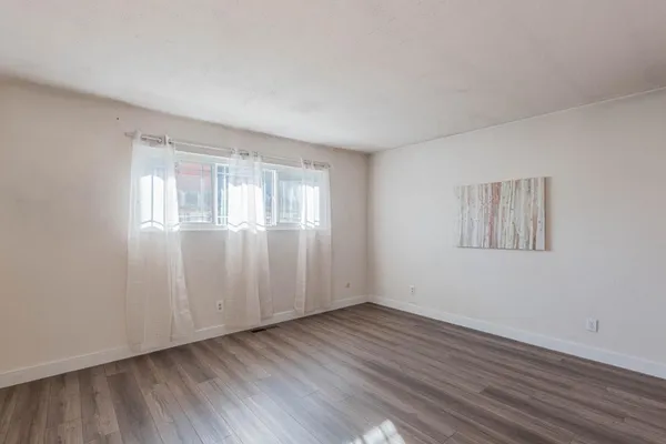 an empty room with wooden floor and windows