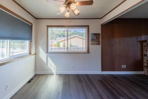 a view of an empty room with wooden floor and a window